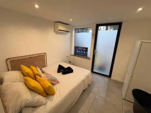 a room with a bed with yellow pillows on it at studio indépendant dans une villa in Aimargues