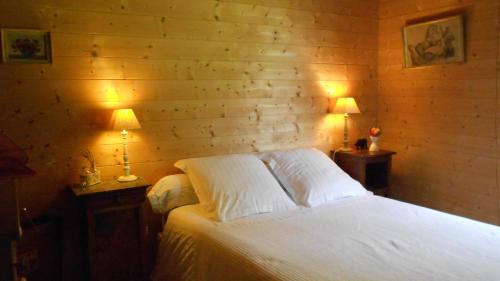 a bedroom with a white bed with two lights on it at La maison bois in Chaon