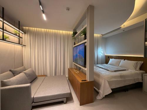 a bedroom with a bed and a tv and a couch at Sky Designer Alphaville - 1611 in Barueri