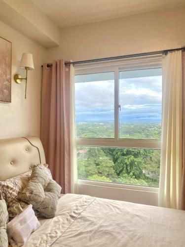 a bedroom with a large window with a bed and a view at H4R1 Luxe Haven in Bacolod