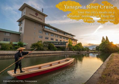 a man is rowing a boat in a river at KAMENOI HOTEL Yanagawa in Yanagawa