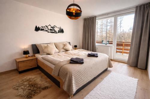a bedroom with a bed and a large window at Hagy Apartments in Vysoké Tatry