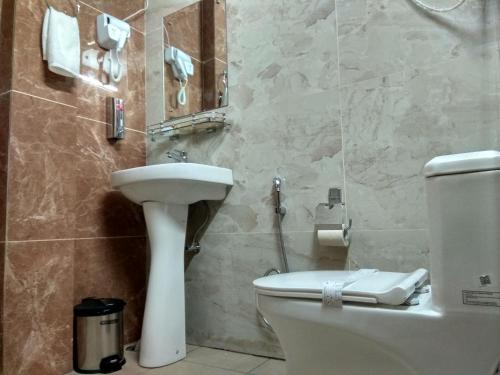 a bathroom with a white toilet and a sink at Peaks n Pines in Nainital
