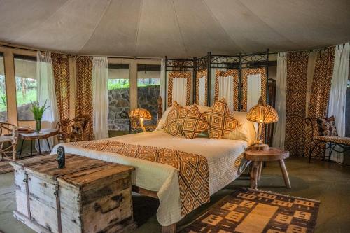 a bedroom with a bed and a table and windows at Dolly Farm & River Camp, Luxury Tents in Usa River