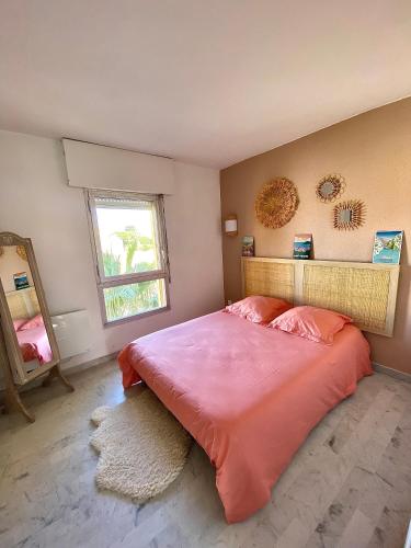 a bedroom with a large pink bed with a window at appartement T2 cabine cap d'agde in Cap d'Agde