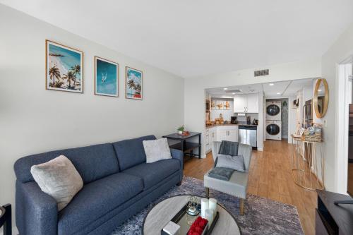 a living room with a blue couch and a kitchen at Luxe Stay Water & City View in Downtown Ft Myers in Fort Myers