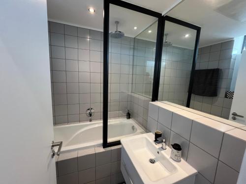 a bathroom with a tub and a sink and a mirror at The Happy Chameleon in George
