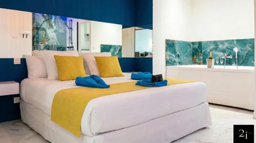 a large white bed with blue and yellow pillows on it at LE 21 - Suite SPA Premium - Jacuzzi Privatif & Vue Rhône in Vienne