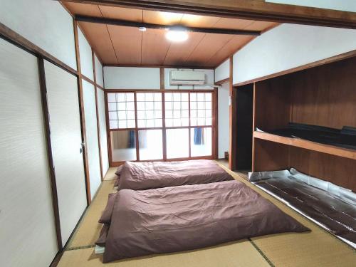 an empty room with two beds and a television at OZigaoka Guest House in Otsu