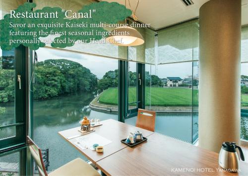 a conference room with a table with a view of a river at KAMENOI HOTEL Yanagawa in Yanagawa
