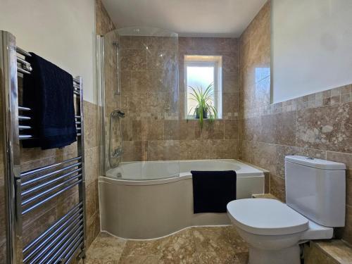 a bathroom with a tub and a toilet and a sink at StayZen Apartments - Luxury Central Apartment with Parking - sleeps 8 in Woking
