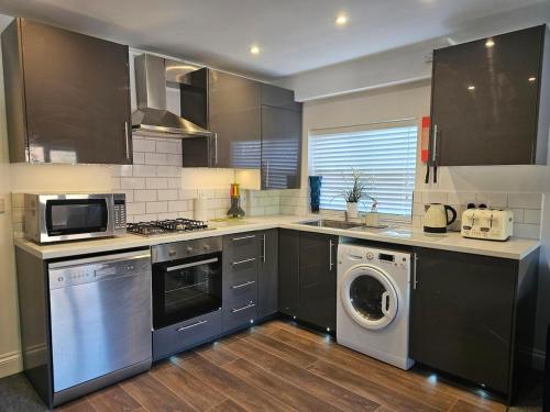 a kitchen with a washing machine and a washer at StayZen Apartments - Luxury Central Apartment with Parking - sleeps 8 in Woking