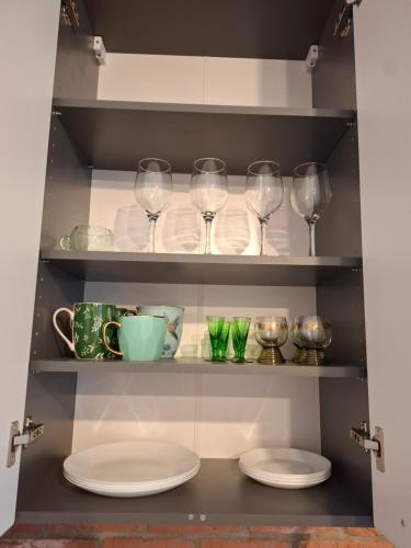 a pantry with plates and wine glasses on shelves at Jūras ielas apartamenti in Limbaži
