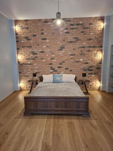a bedroom with a large bed in front of a brick wall at Jūras ielas apartamenti in Limbaži