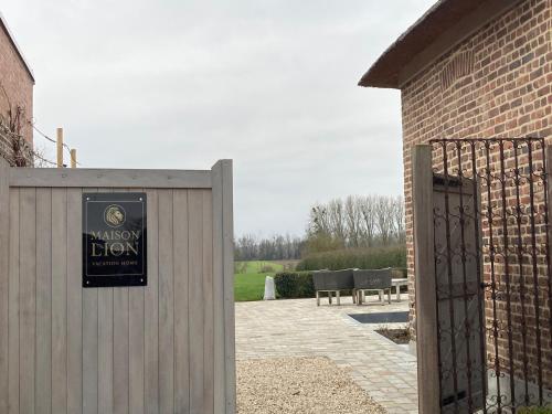 a sign on a fence next to a building at Maison Lion Luxe gastenverblijf in Borgloon