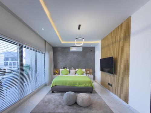 a bedroom with a green bed and a large window at Luxury Executive Balcony Suite at THE HIDDEN DOMUS I Elmina Suite in Accra