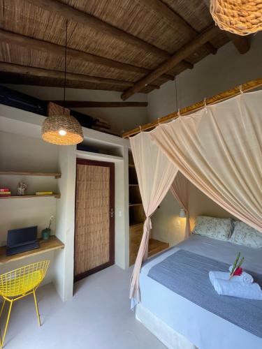 a bedroom with a bed and a table and a chair at MAHAGUA Casa Holística - Jambreiro, Caraiva, BA in Porto Seguro