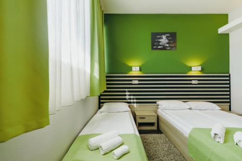 two beds in a room with green walls at Altus Hotel & Spa in Praid