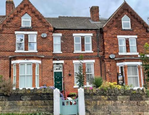 a brick house with a white fence in front of it at Runcorn Jubilee Guest House in Runcorn