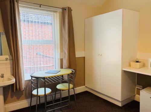 a room with a table and two stools in front of a window at Runcorn Jubilee Guest House in Runcorn