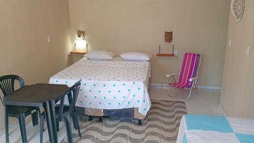 a small room with a bed and a table and chairs at POUSADA GOLFINHO FLECHEIRAS Ce in Trairi