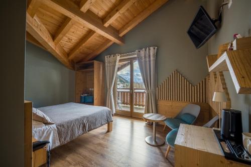 a bedroom with a bed and a desk and a television at Alpen Chalet - Charme Mountain Hotel - in Schilpario