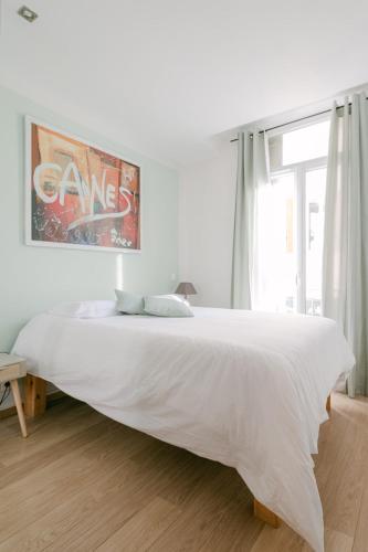 une chambre blanche avec un grand lit blanc et une fenêtre dans l'établissement L'Anita - Hyper Centre Cannes, à Cannes