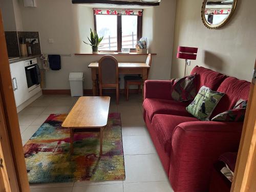 a living room with a red couch and a table at Lind End Cottage in Broughton in Furness