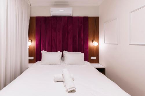 a bedroom with a white bed with a towel on it at מילה בוטיק - סוויטה מהממת עם 2 חדרי שינה, מתחם מקורה עם בריכה מחוממת, ג'קוזי ספא וסאונה! in ‘Ein Ya‘aqov