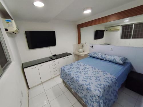a bedroom with a bed and a flat screen tv at Essenza Suites Natal in Natal