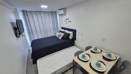 a small bedroom with a bed and a table at Apartamento Maré Alta in Tamandaré