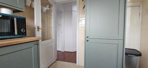 a kitchen with a microwave and a door to a hallway at Spacious Home Near Wembley, Free Parking, Close to Tube, Garden in Pinner