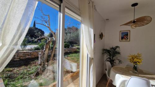 a dining room with a glass door leading to a garden at Logement cosy avec piscine chauffée, jacuzzi, jardin et climatisation in Flayosc