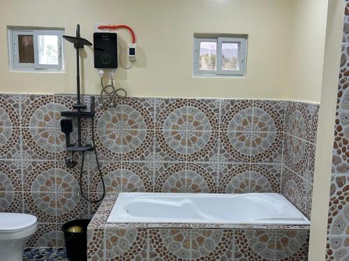 a bathroom with a bath tub and a toilet at Scarlett Near Mount Zion Laguit Padilla in Bugallon