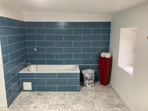 a blue tiled bathroom with a tub in a room at Bastide Armande in Dénat