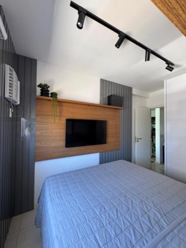 a bedroom with a bed with a tv on the wall at Apartamento Moderno uma quadra do mar in Vila Velha
