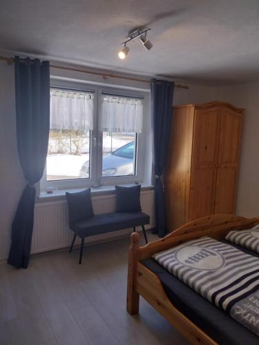 a bedroom with a bed and a chair and a window at Fewo Helga in Glowe