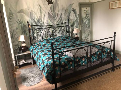 a bedroom with a black bed with a tropical wallpaper at Chez l habitant in Méré
