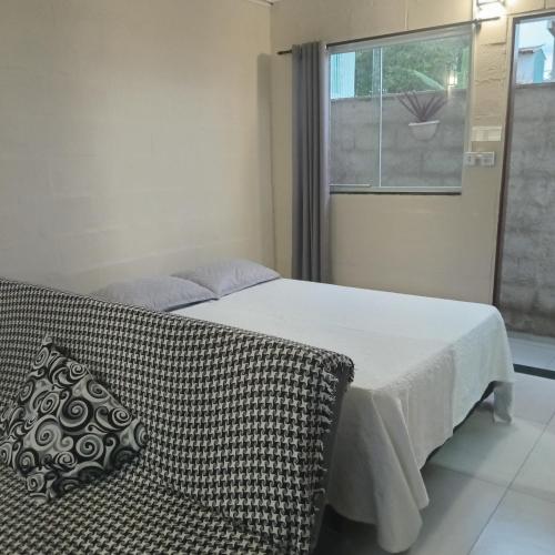 a bedroom with a bed with a couch and a window at Loft Caminho de Búzios in Cabo Frio