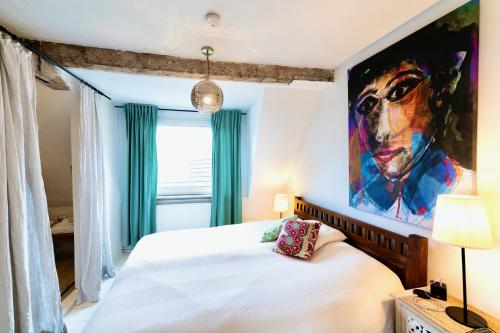 a bedroom with a white bed with a painting on the wall at Schuhmacherei Rooms in Oestrich-Winkel
