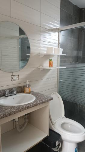 a bathroom with a sink and a toilet and a mirror at Refugio Volcán Tungurahua in Ambato