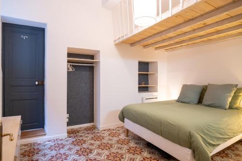 a bedroom with a green bed and a black door at La Calade Charming Apartment in Nîmes