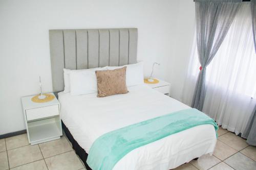 a bedroom with a white bed with a blue blanket at 1 bed apartment in Harare CBD in Harare