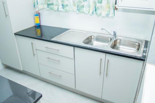 a kitchen with white cabinets and a sink at 1 bed apartment in Harare CBD in Harare