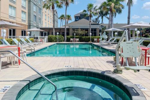 a swimming pool at a hotel with chairs and tables at Hilton Garden Inn Sarasota-Bradenton Airport in Sarasota