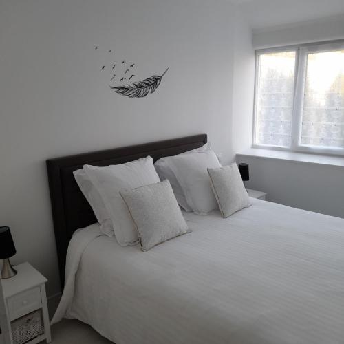 una camera da letto con un letto con lenzuola e cuscini bianchi di Le Caloan a Maen Roch
