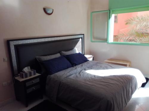 Un dormitorio con una cama con almohadas azules y una ventana en Kim Apartment, en Marrakech