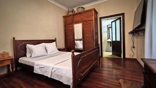 a bedroom with a bed with a wooden headboard and a mirror at Soa Refuge in Antananarivo