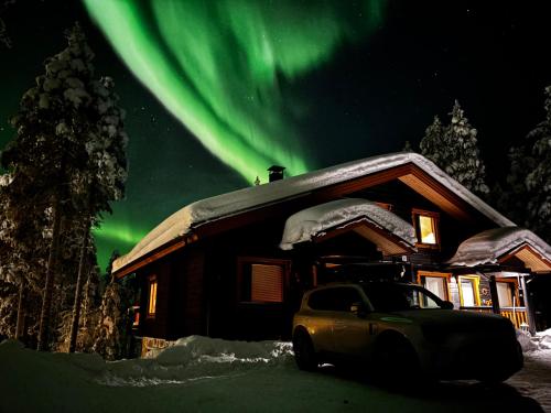 a car parked in front of a cabin under the aurora at Villa Immellompolo in Levi