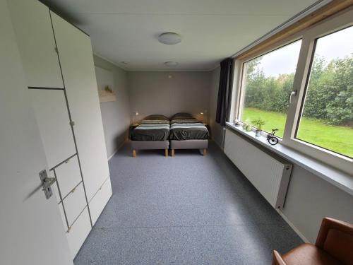 a small room with two beds and a window at Vrijstaande ruime familiewoning landelijk gelegen in Lewedorp